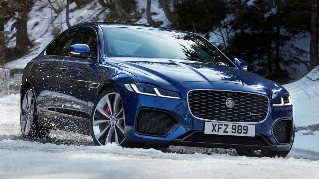 A blue 2020 Jaguar XF driving down a snow-covered road.